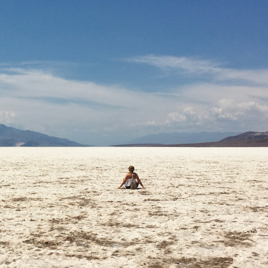 Death Valley person sitting in the middle of the white salt flats landscape